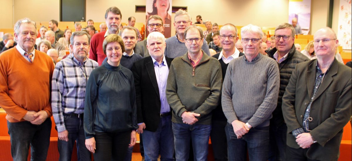Södras viltgrupp och medverkande på mötet som hölls i Växjö. 12 män och en kvinna står längst fram i möteslokalen. Åhörare i bänkar i bakgrunden.
