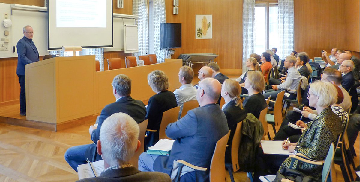 Mats Blomberg står i talarstolen i ett mötesrum i Sveriges riksdag och talar till deltagarna i hearingen.