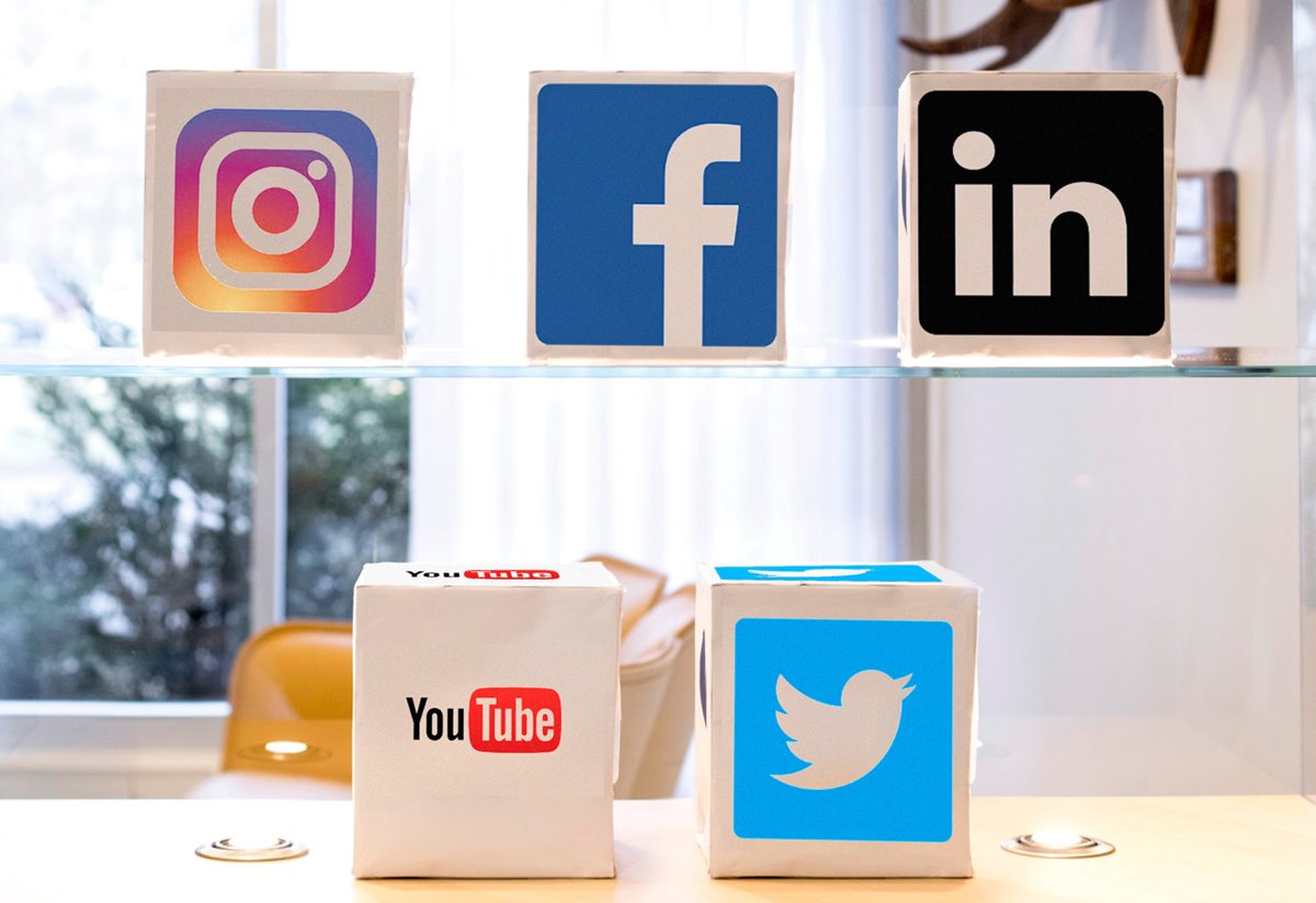 Fem kuber av papper i ett glasskåp med genolmskinlig bakgrund. Kuberna visar symbolerna för de sociala medierna Instagram, Facebook, LinkedIn, YouTube och Twitter.