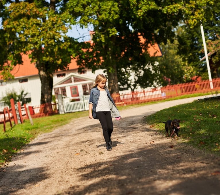Kvinna gående framför familjeskogsbruk hus