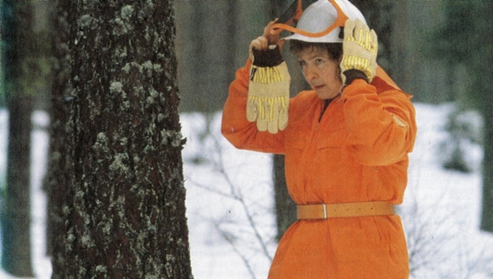 Kvinnlig skogsarbete med hjälm.