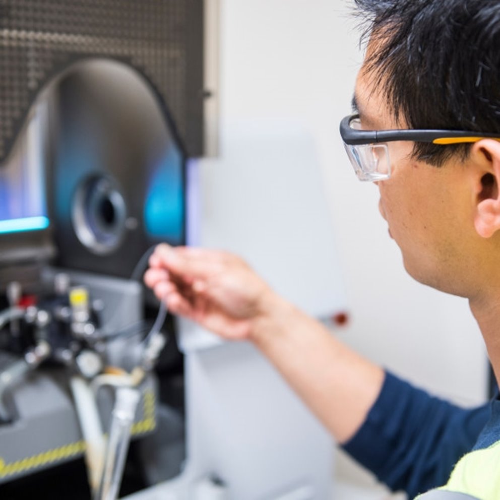 Manlig medarbetare justerar maskin