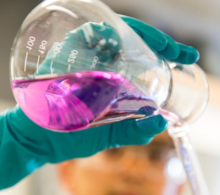 Flaska med rosa vätska hälls ut ur en behållare