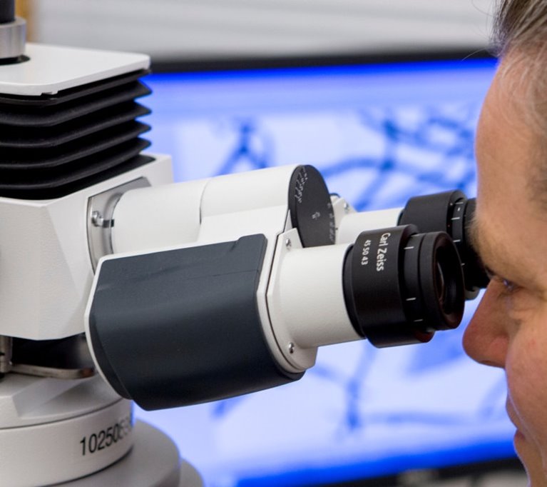 Personen tittar genom mikroskop