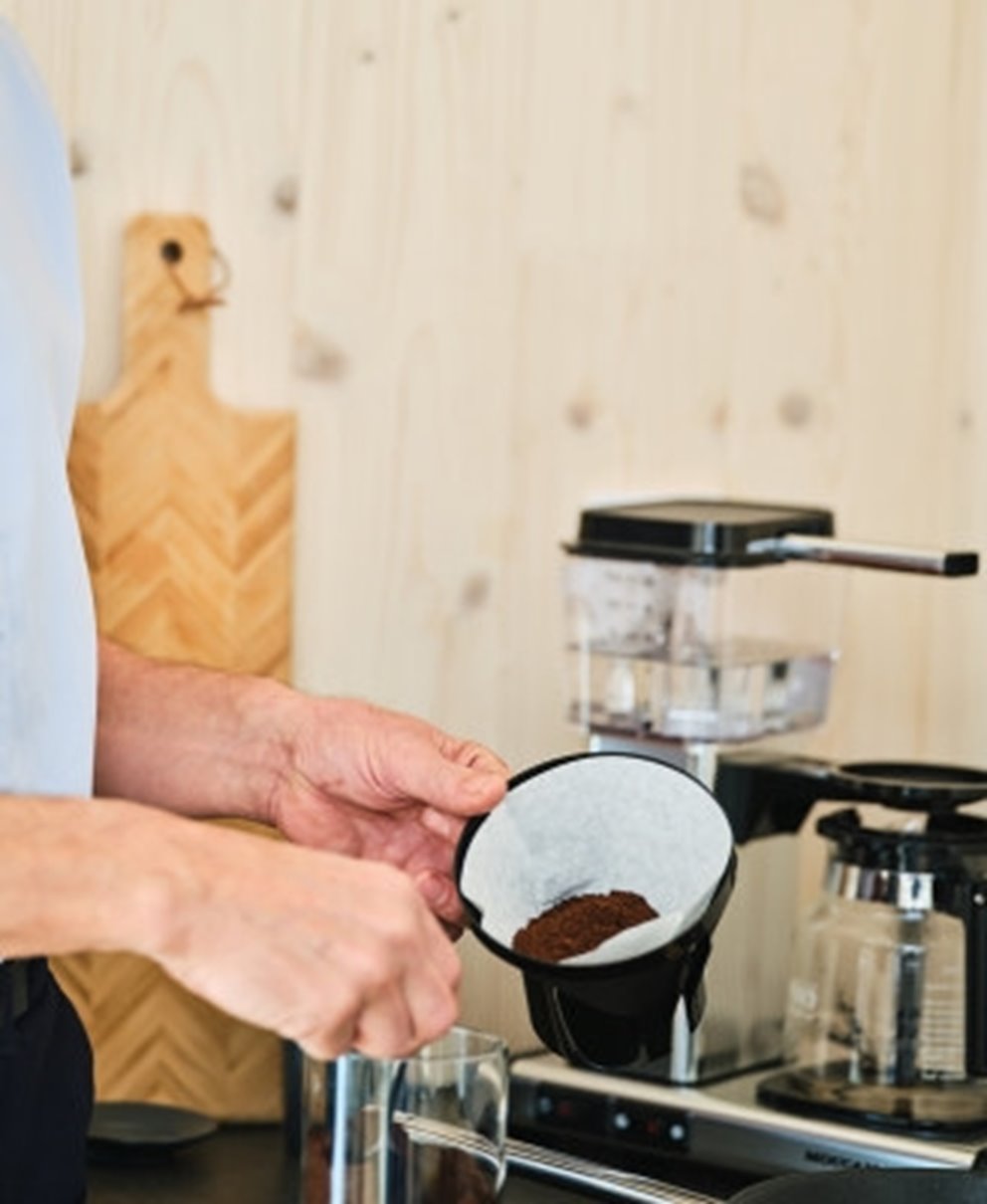 Man öser kaffe i ett kaffefilter