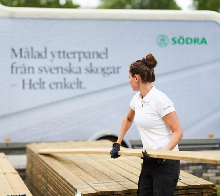 Kvinna plockar tryckimpregnerad trall 28x120 mm släp i bakgrunden