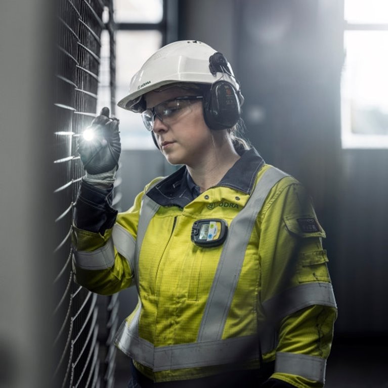 Kvinna i indsutrimiljö med skyddsutrustning