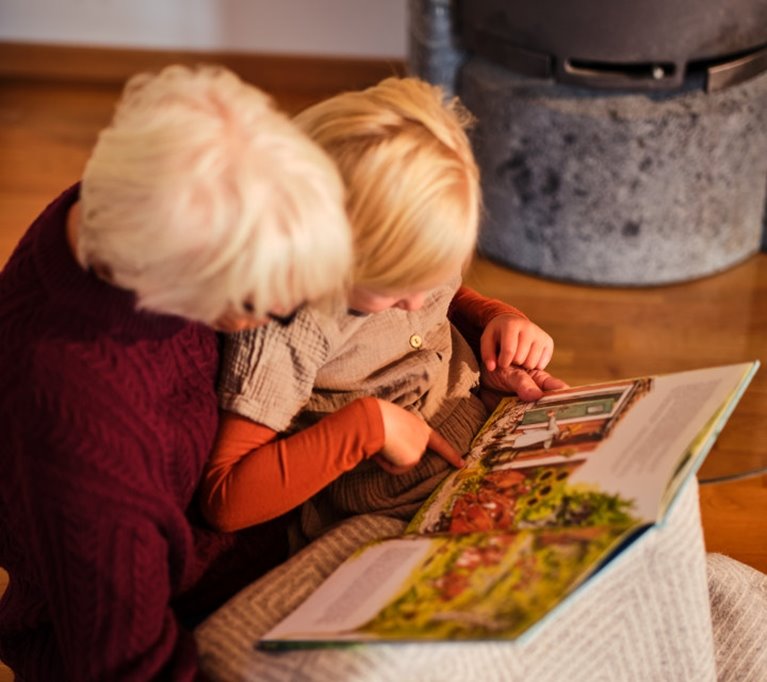 Mormor läser bok och myser framför brasan.