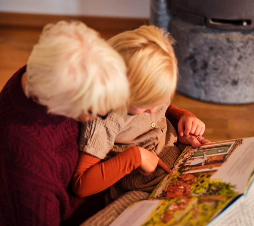 Mormor läser bok och myser framför brasan.