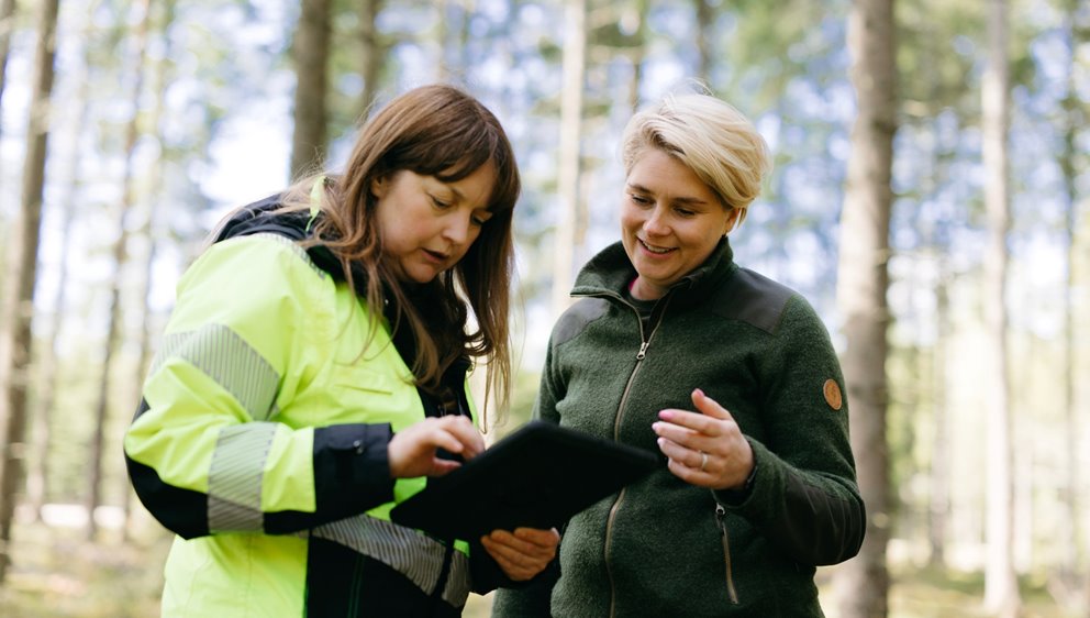 Rådgivare Linn Spjuth och medlem Marielle Bergman tittar på Ipaden i skogen.