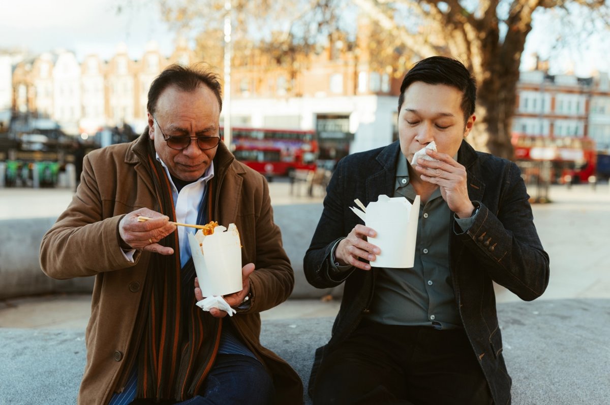 Two people eating form paper boxes